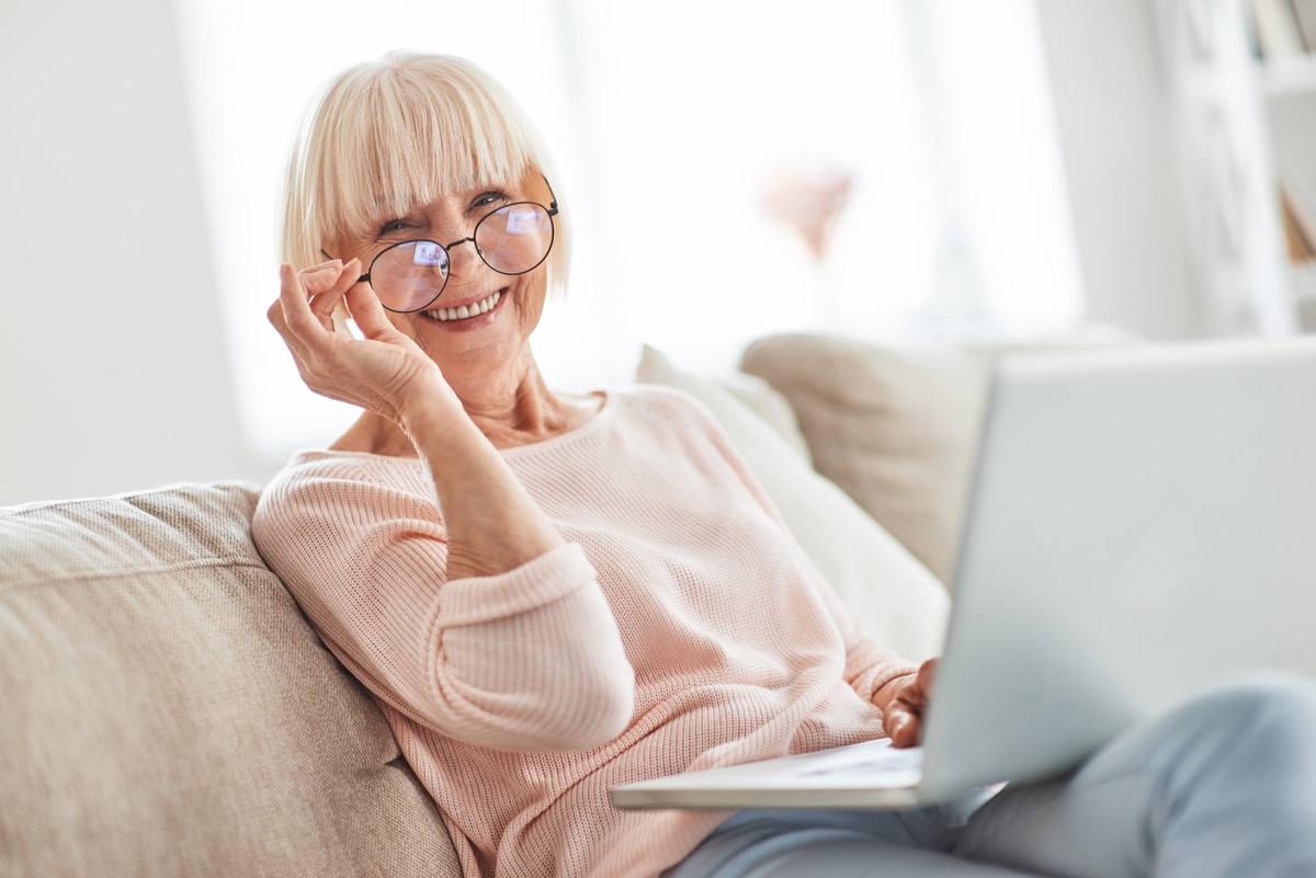 on the retirement. beautiful senior woman looking at camera and smiling while relaxing on the couch at home