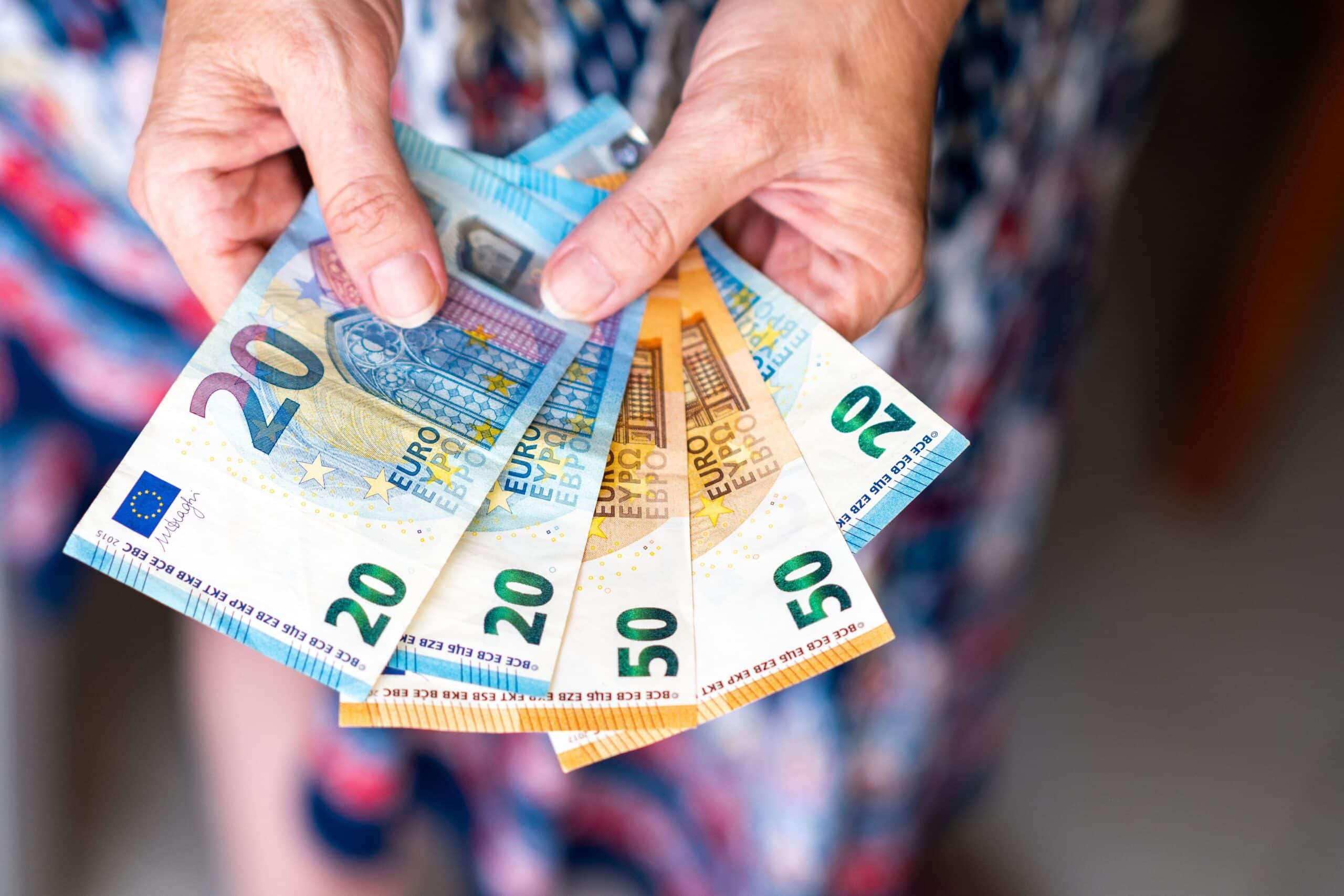 close up shot of hands holding 20 and 50 euro banknotes